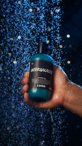 Image shows a model holding a bottle of the shower gel under a shower.